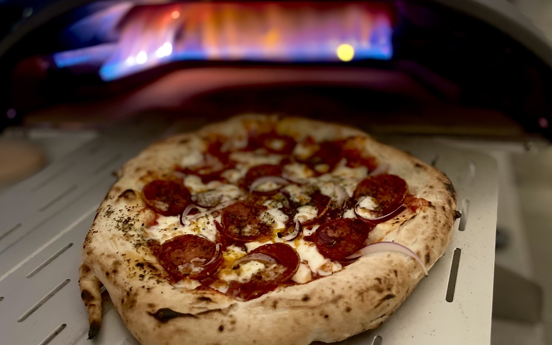 Jespers pizza på pizzaskovlen foran Ooni Koda 16 med gasflammen tændt