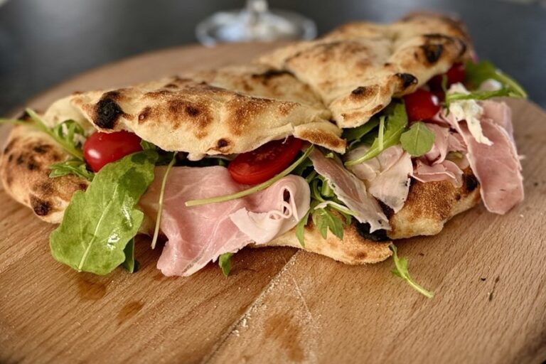 Jespers pizzasandwich med skinke, rucola og cherrytomater på et træbræt